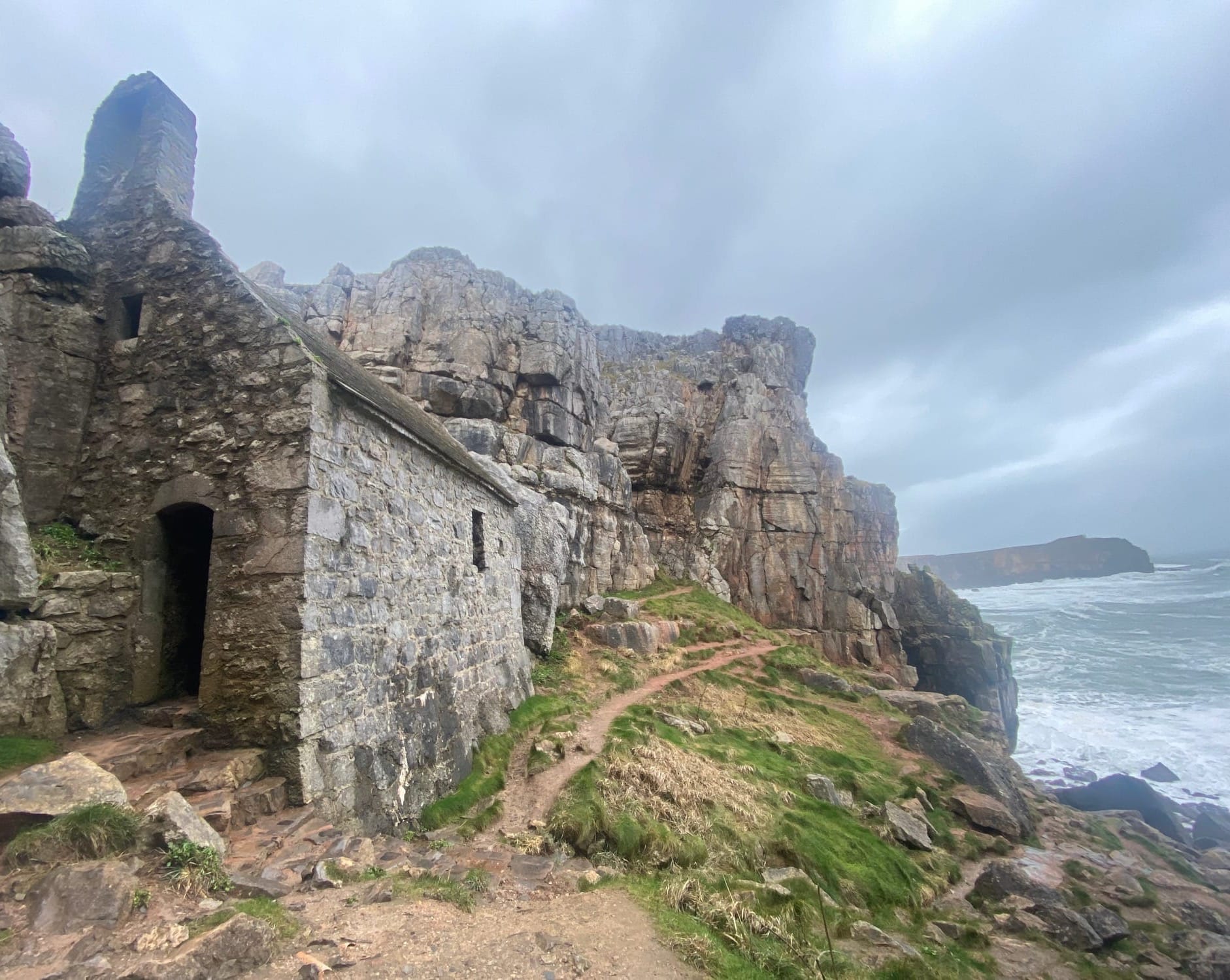 A photo of a 6th century stone chapel built into a cliff above the crashing waves below