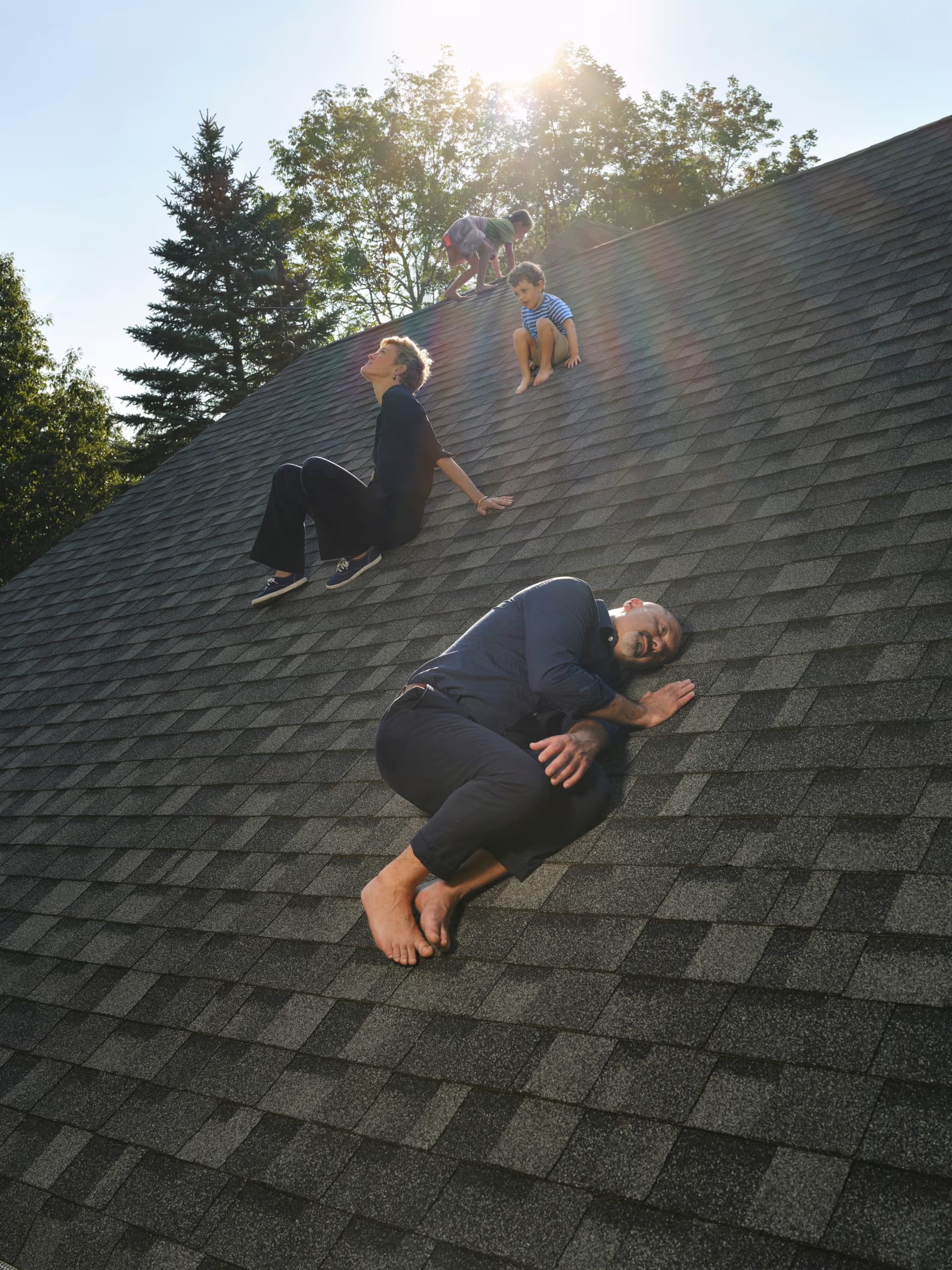 A really weird photo of Boris and Jessica, the couple from the show Couple's Therapy, and their children, all randomly on the roof of their house? Boris is lying on his side, looking depressed, while Jessica looks up at the sky, full of hope. Meanwhile, their children are climbing over the edge of the roof and making me nervous they're going to fall off! What is this picture??