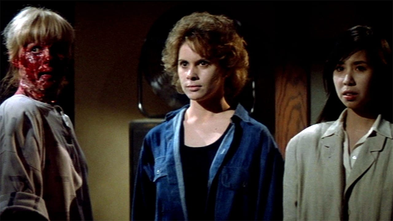 A still from Prince of Darkness that shows 2 normal-looking lovely ladies standing next to a woman whose entire face has melted off, revealing a bloody mess